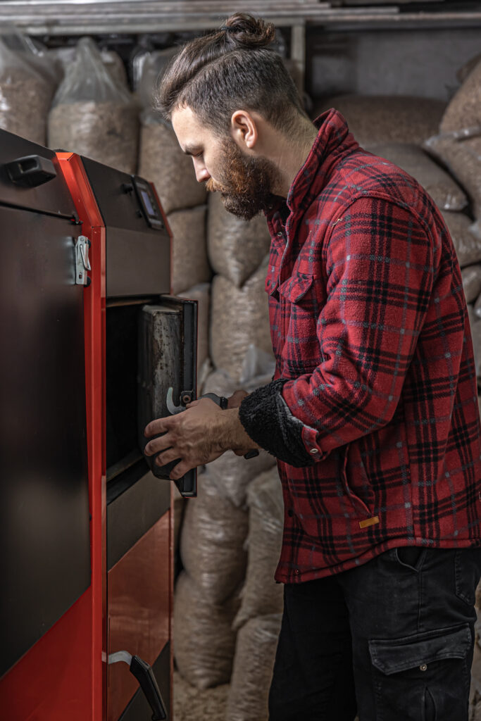 the young man with solid fuel boiler, working with biofuels, economical heating.